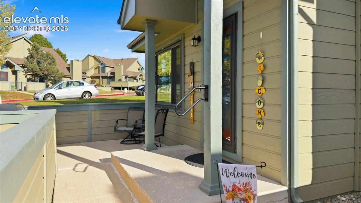 Covered exterior porch featuring horizontal siding, a concrete foundation, a support pillar with a mounted handrail, and an integrated exterior light fixture