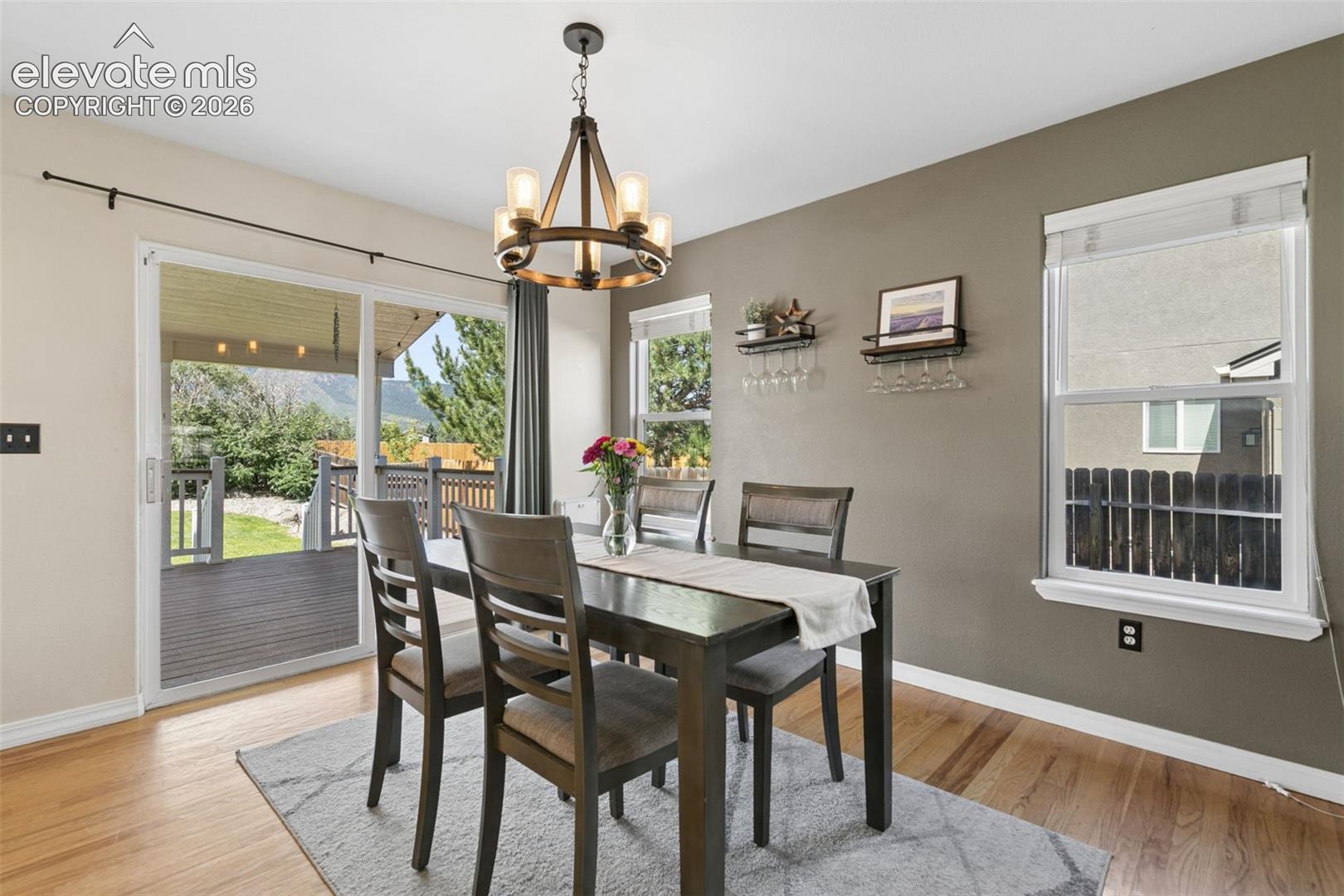 Hardwood flooring, sliding glass door, outdoor deck, chandelier lighting, and a neutral color palette