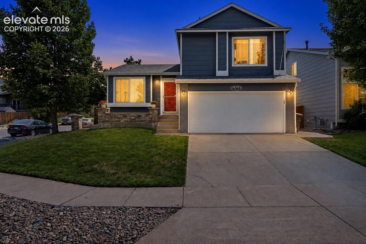 Two-story residence with a two-car garage, concrete driveway, and a stone facade detail