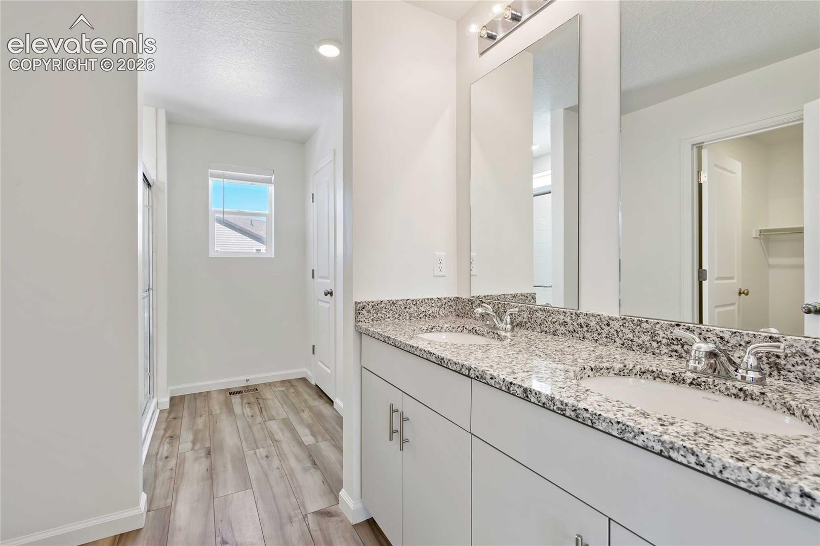 Dual vanity with granite-style countertop, white cabinetry, and undermount sinks
*photos of a model home*