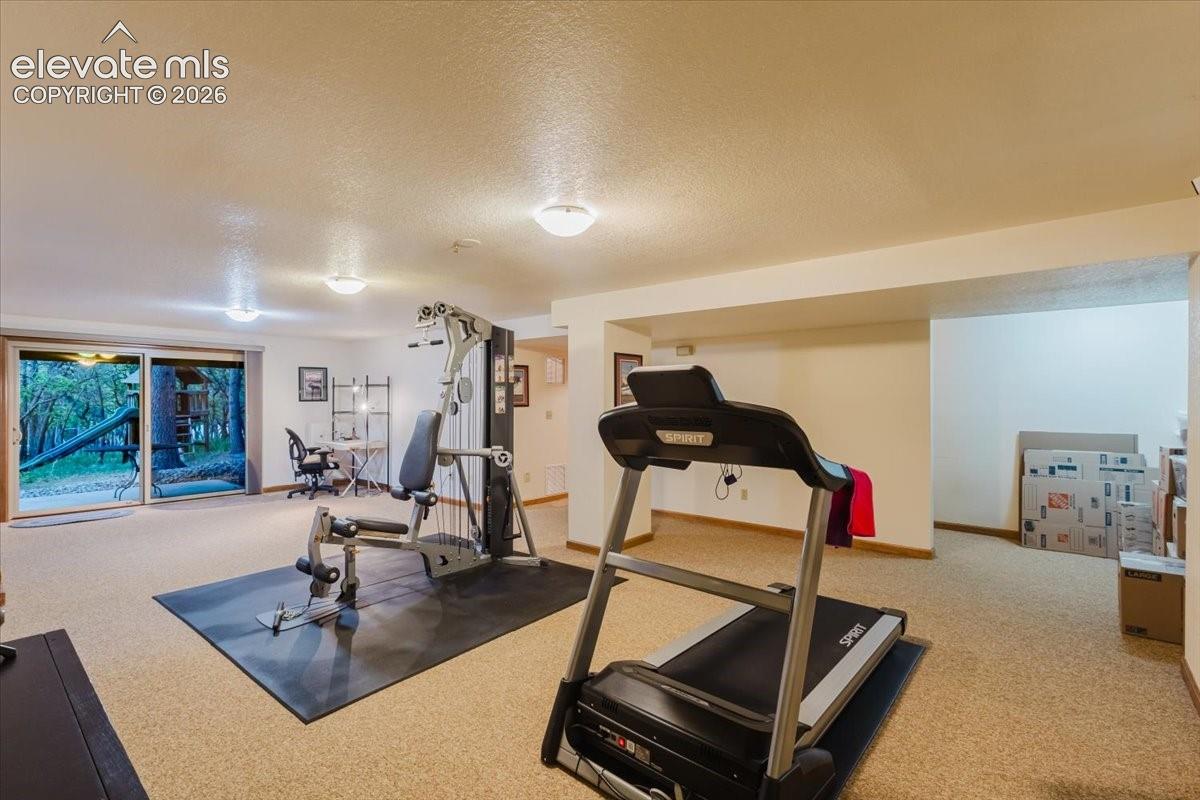Spacious lower-level room featuring light-colored carpeting, recessed lighting, and a walk-out patio door