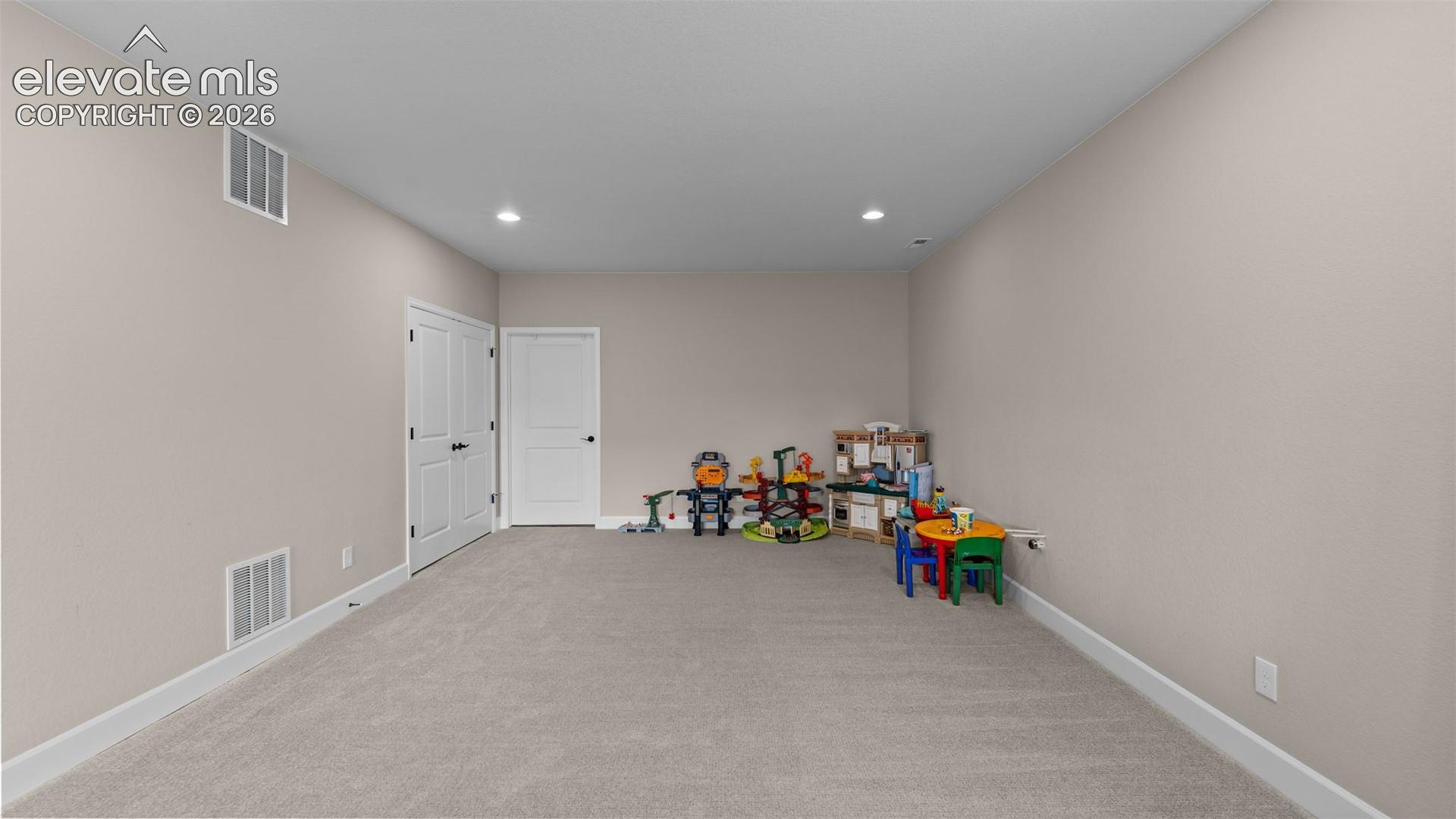 Spacious room with neutral wall tones and recessed lighting