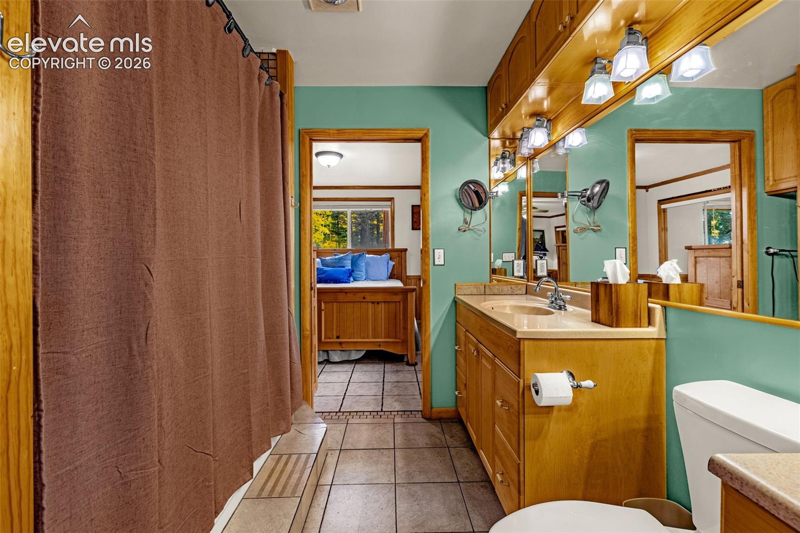 Bathroom featuring a built-in vanity with wood cabinetry, full-width vanity mirror, integrated lighting, and tile flooring
