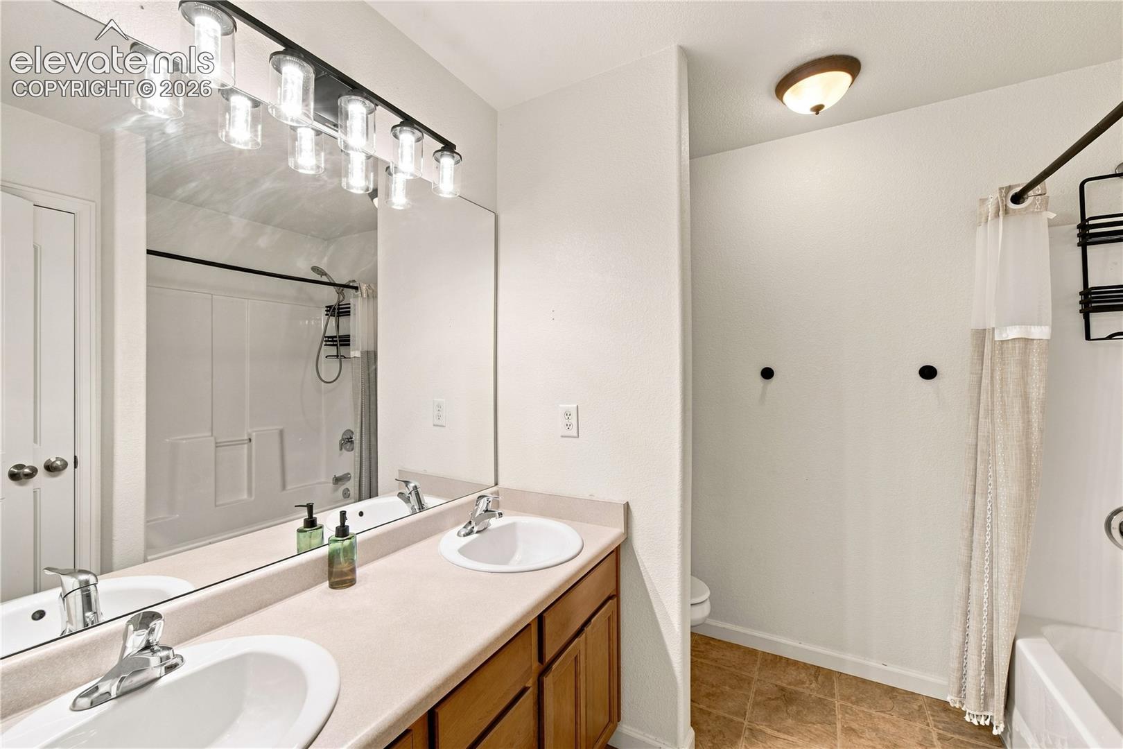 Dual vanity with integrated sinks, full-width mirror, and multi-light fixture