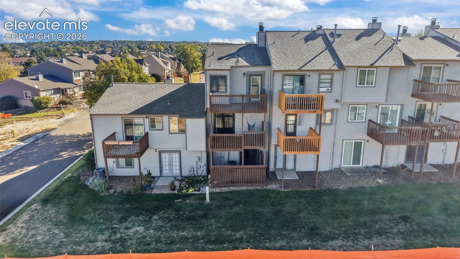 Multi-story exterior featuring wood-tone siding, multiple elevated balconies with railing, gabled rooflines, and sliding glass door entries