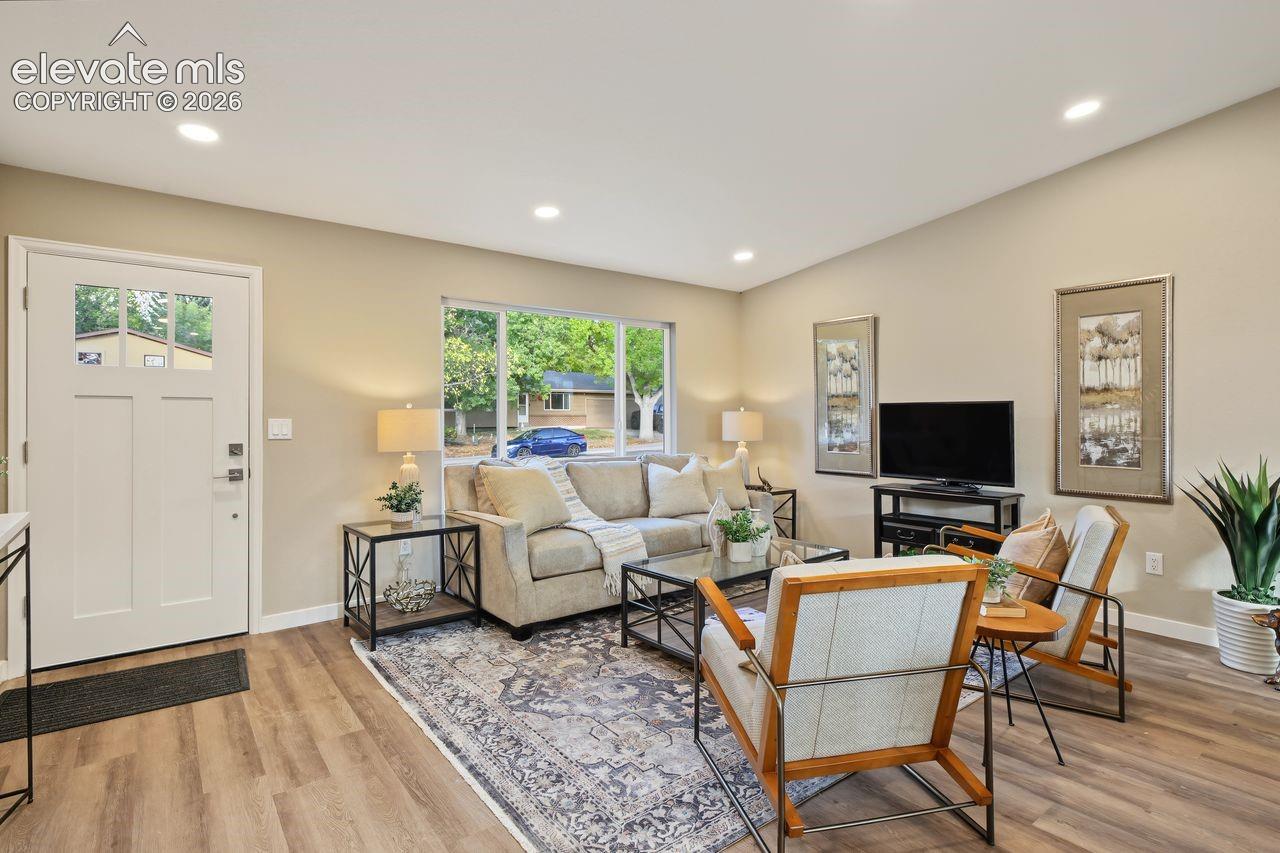Living area featuring wood-finish flooring, recessed lighting, and a large picture window