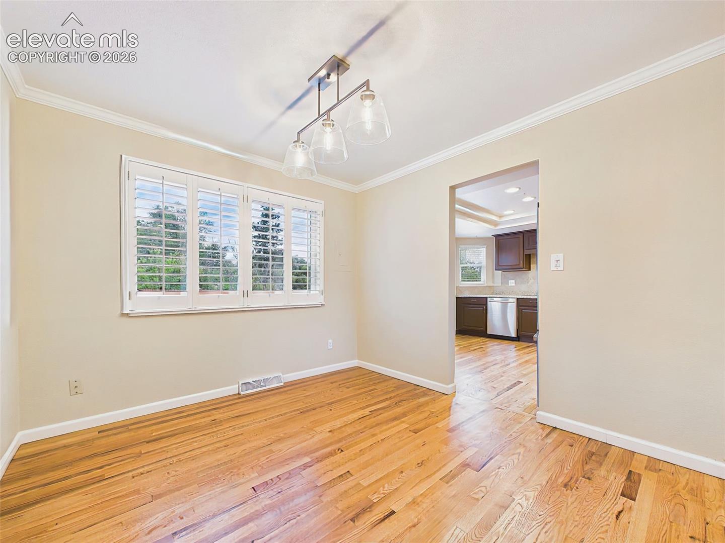 Another view of the dining room highlights its spacious layout, abundant natural light from plantation shutters, and easy flow into the adjacent kitchen.