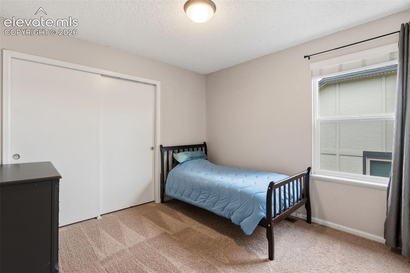 Carpeted flooring with a white sliding door closet, recessed window, and flush mount ceiling light