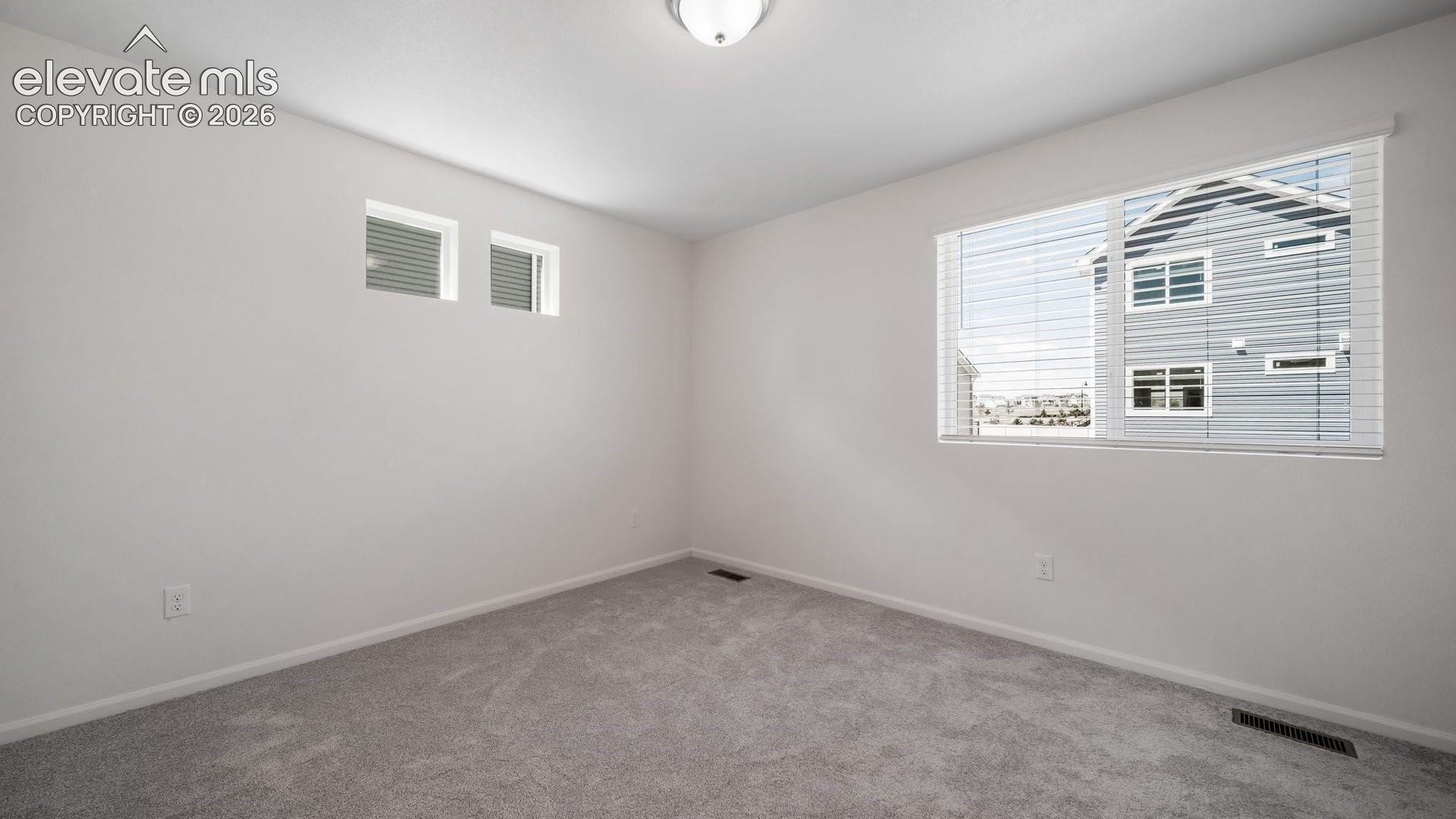 Neutral-toned interior featuring wall-to-wall carpeting, a large picture window with horizontal blinds, and dual transom windows
*photos of a model home*