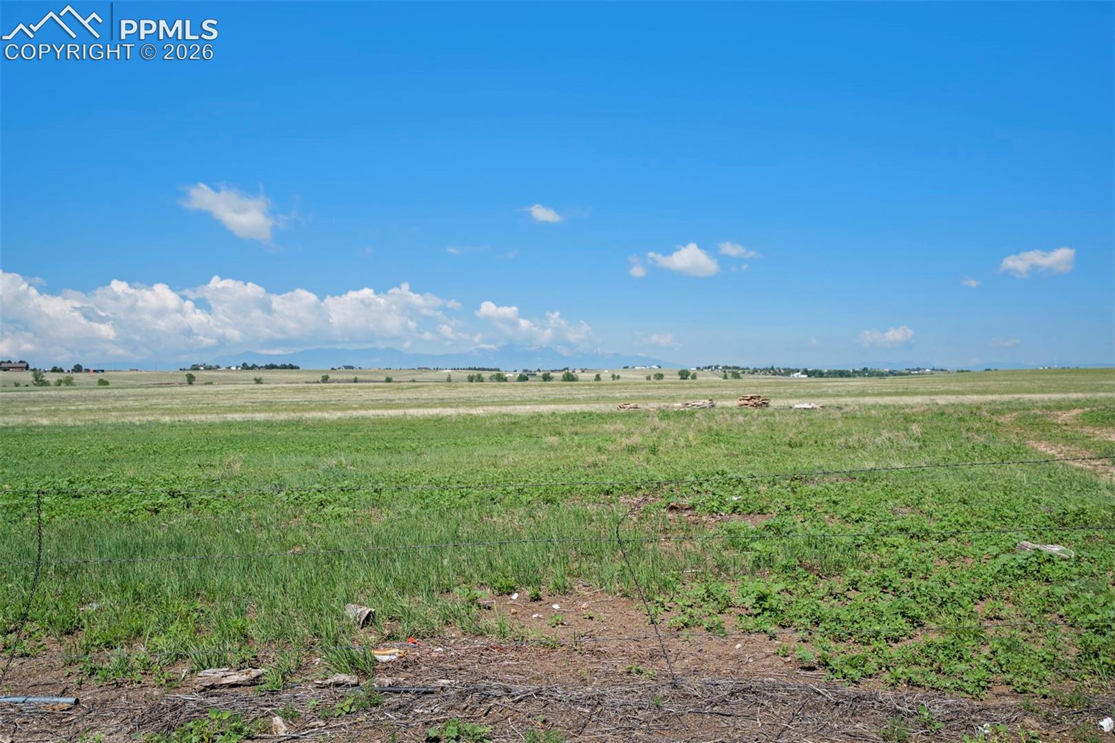 Expansive open field with natural grass and distant mountain ranges under a clear sky