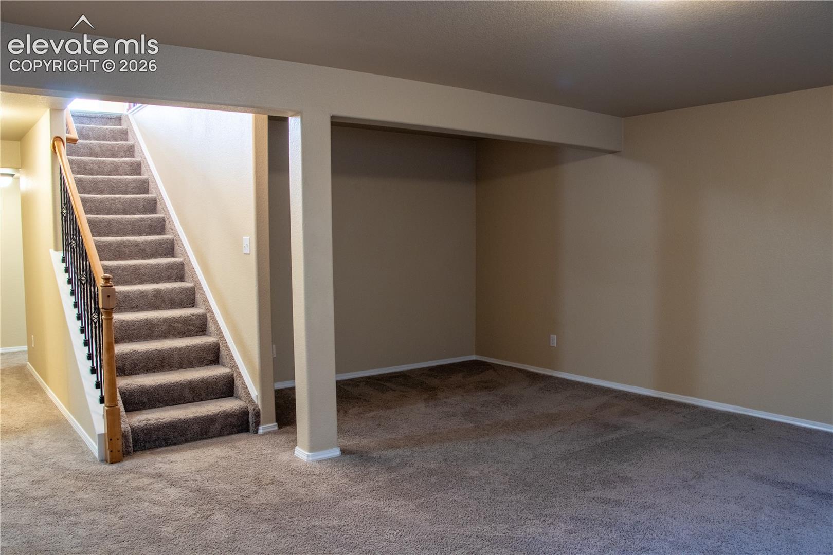 Carpeted staircase with an ornamental metal baluster and wood-finish handrail