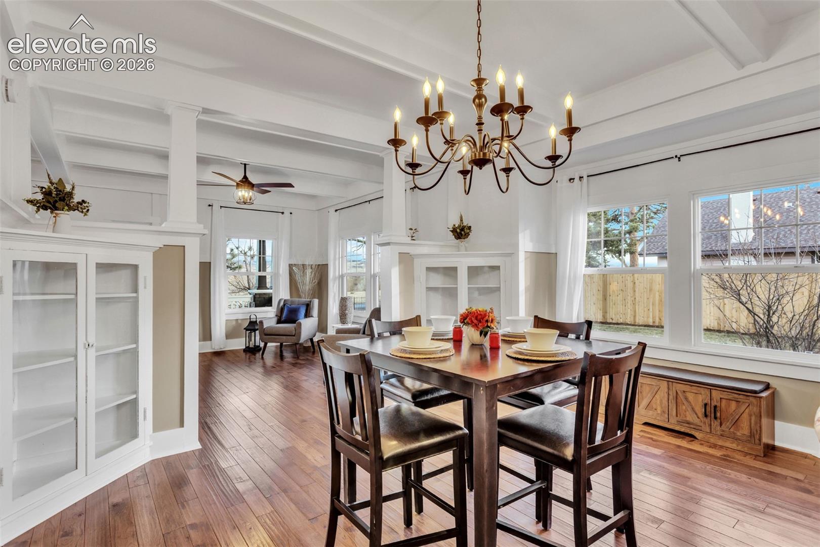 Dining area featuring wood-finish flooring, a coffered ceiling, and a bronze chandelier