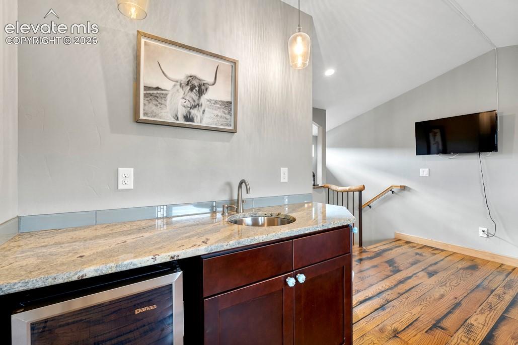 Wet bar with granite countertop, stainless steel sink, and integrated beverage refrigerator
