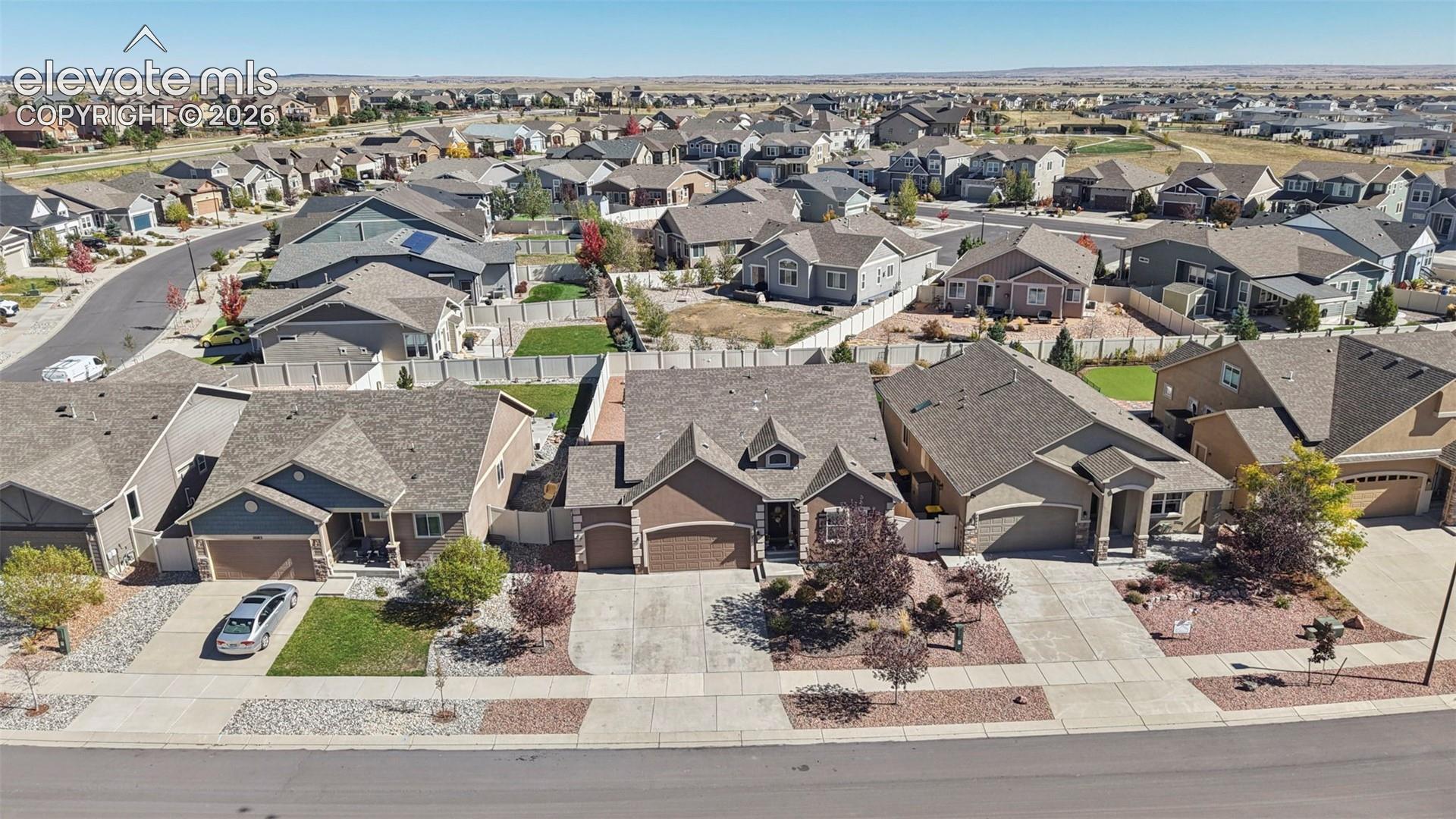 Suburban residential setting featuring multi-gabled rooflines, stone-accented facades, attached multi-car garages, and concrete driveways
