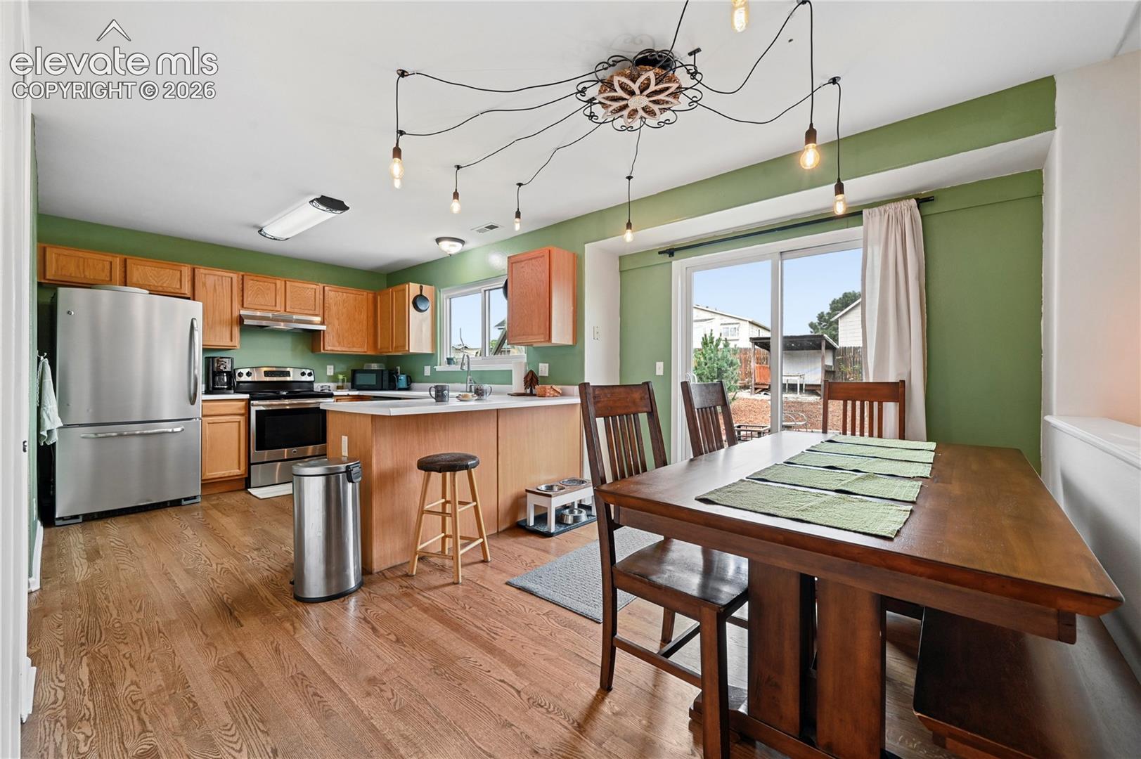 Dining room with custom lighting and easy flow to the kitchen as well as outdoor spaces