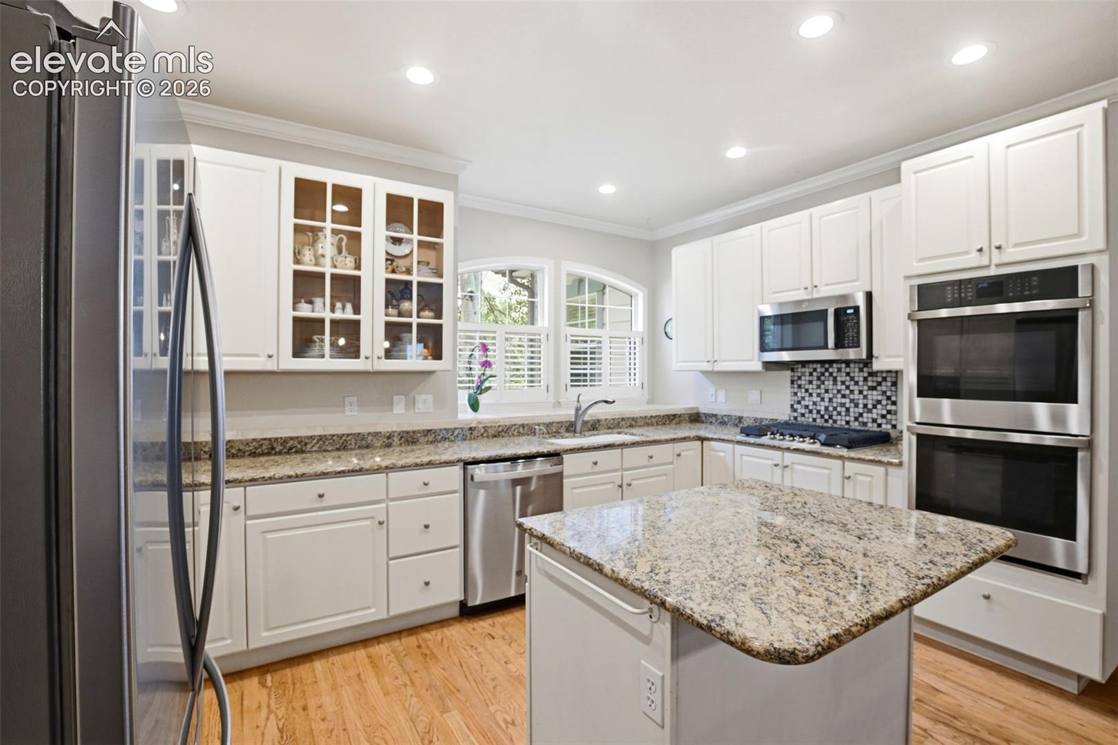 Ktchen featuring granite countertops, a center island, and abundant clean white cabinetry with newer SS appliances.