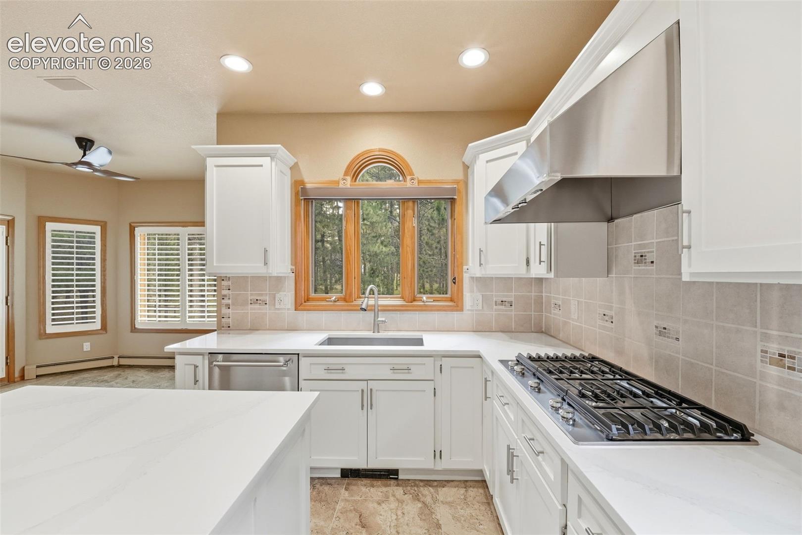 Kitchen featuring white cabinetry, light countertops, stainless steel appliances, a gas cooktop, and an arched window