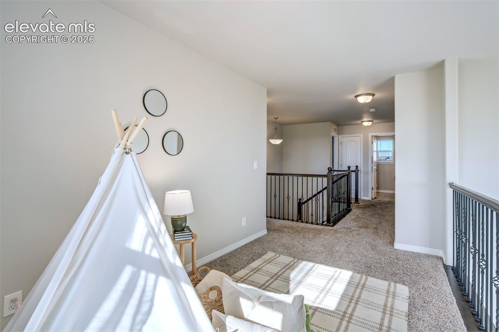 Carpeted loft area with wrought iron railings and recessed lighting