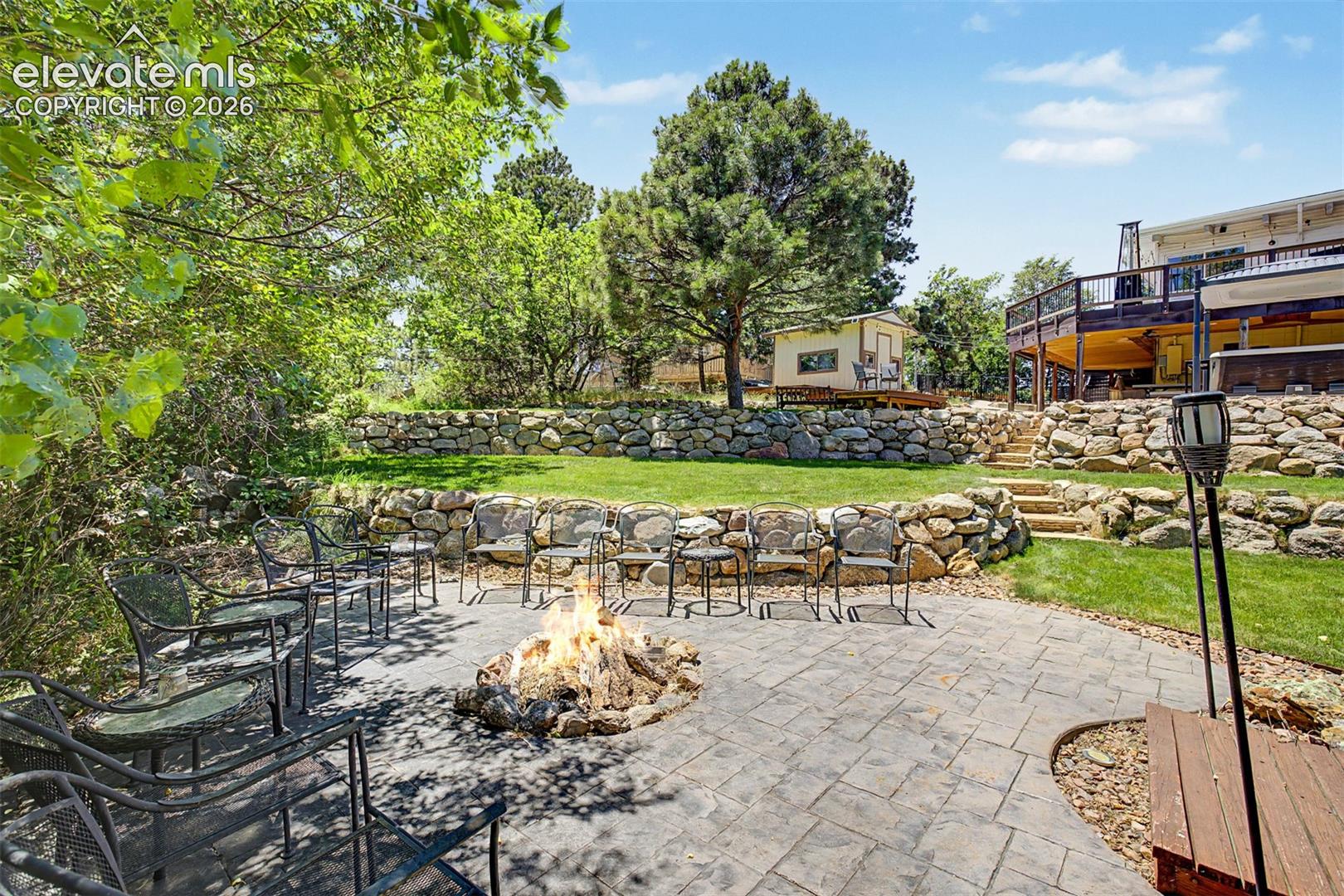From the patio, manicured lawns and stacked-stone walls create distinct outdoor "rooms" throughout the backyard.