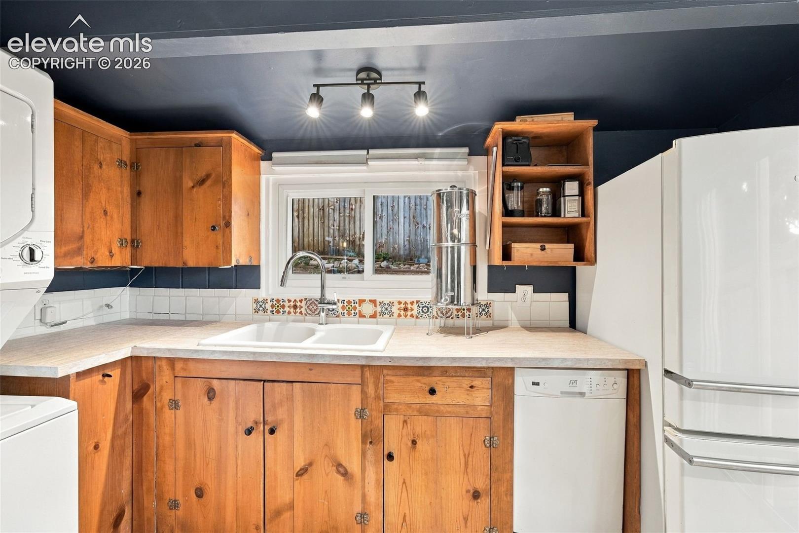 Kitchen featuring natural wood cabinetry, a dual-basin white sink.
