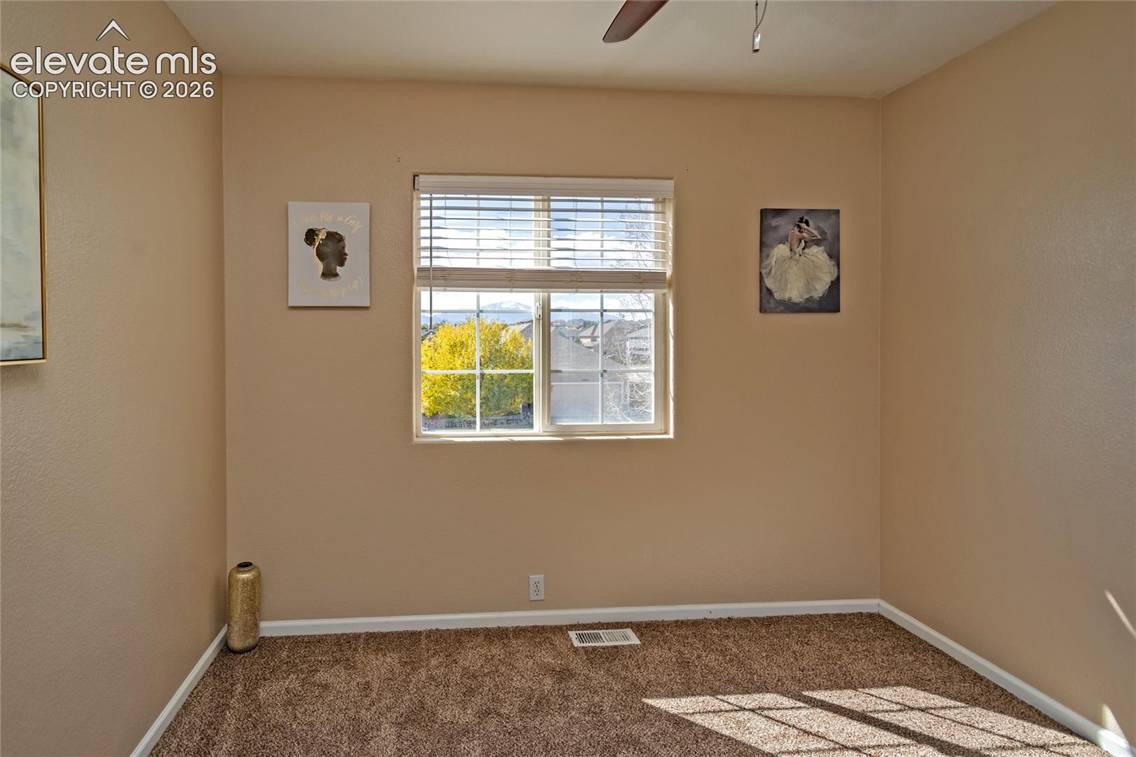 The bright second bedroom features plush new carpeting, blinds, and views of the surrounding autumn trees