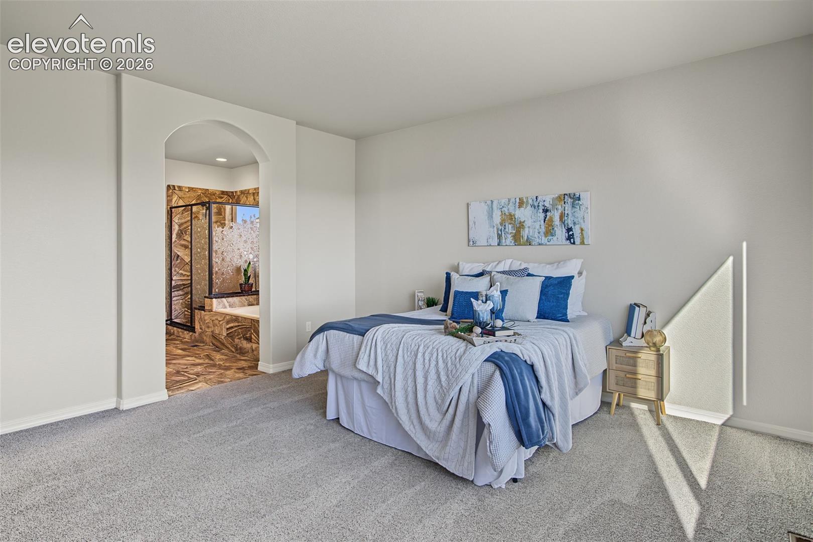 Neutral-toned room featuring plush wall-to-wall carpeting and an arched entryway leading to a stone-tiled enclosure with a glass-paneled shower