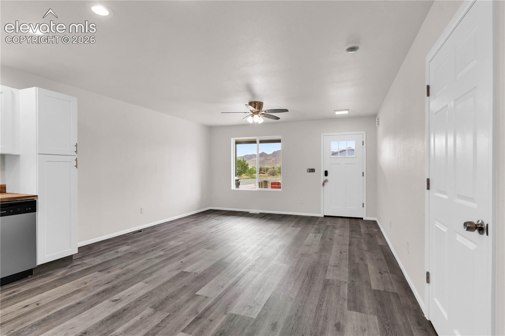 Wood-finish flooring, white shaker-style cabinetry, recessed lighting, ceiling fan with light kit, and exterior mountain scenery