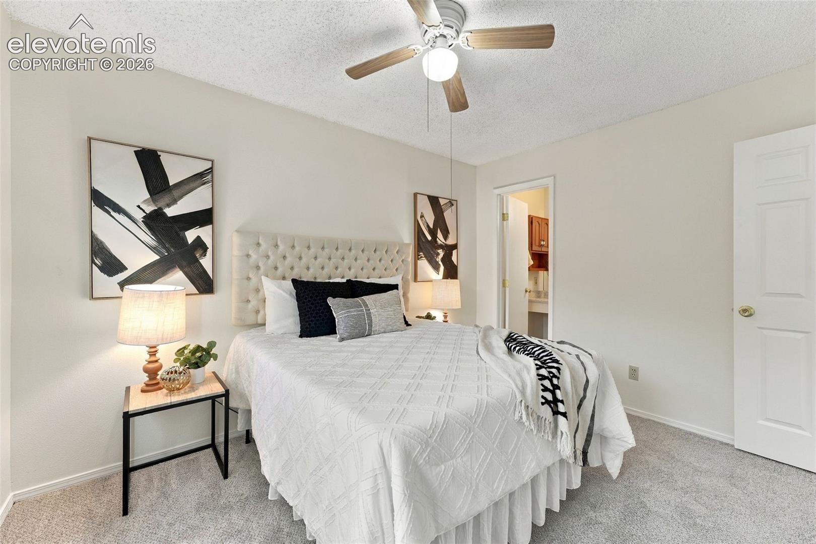 Neutral interior room featuring neutral-toned carpeting, a white paneled door, and a ceiling fan with integrated lighting