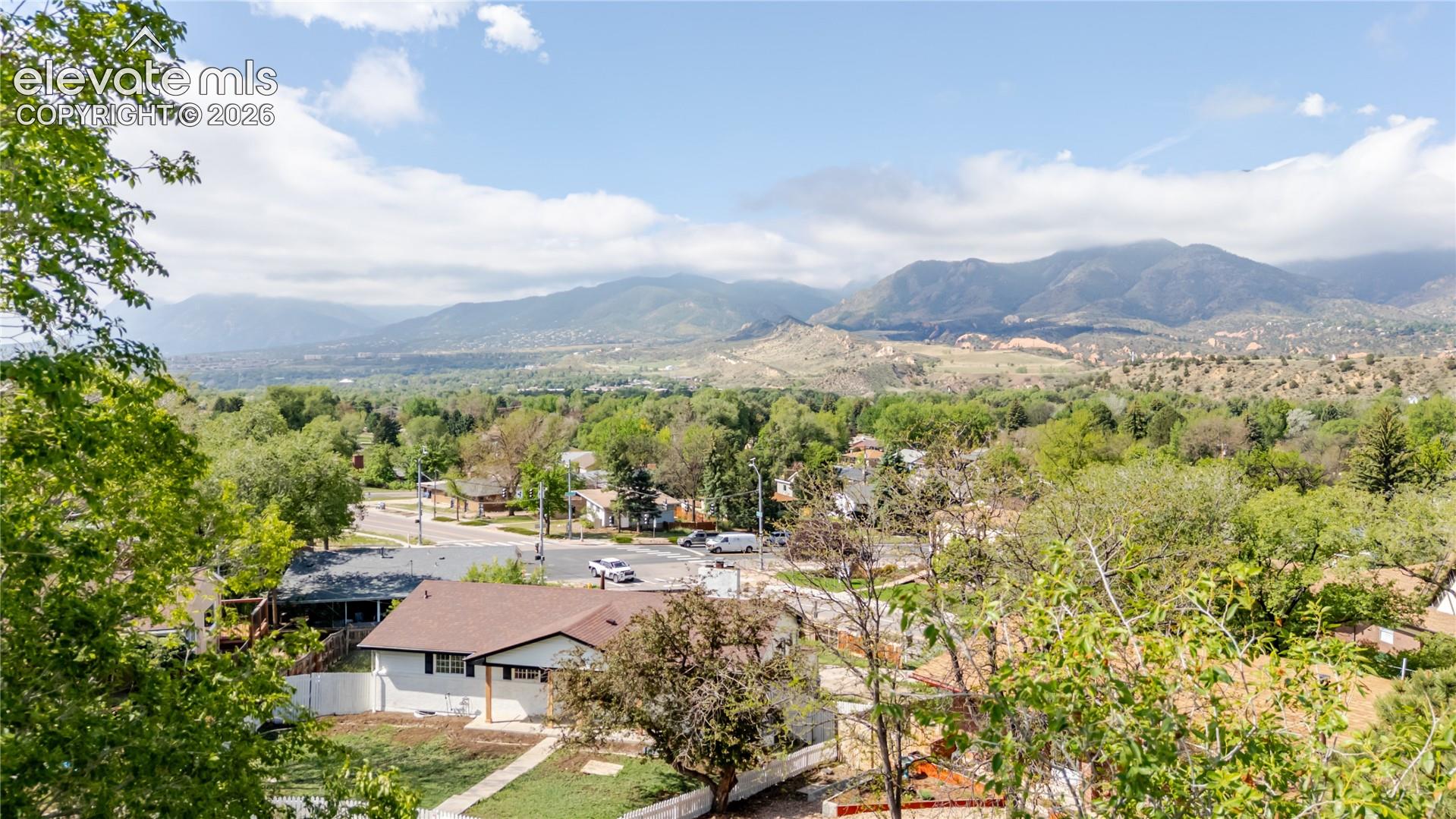 Expansive mountain scenery framing a residential area with varied rooflines and abundant trees