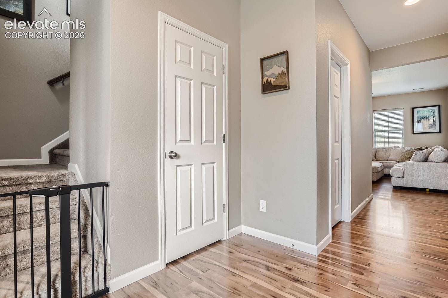 Interior hall featuring wood-finish flooring, neutral wall tones, multi-panel interior doors, and carpeted staircase