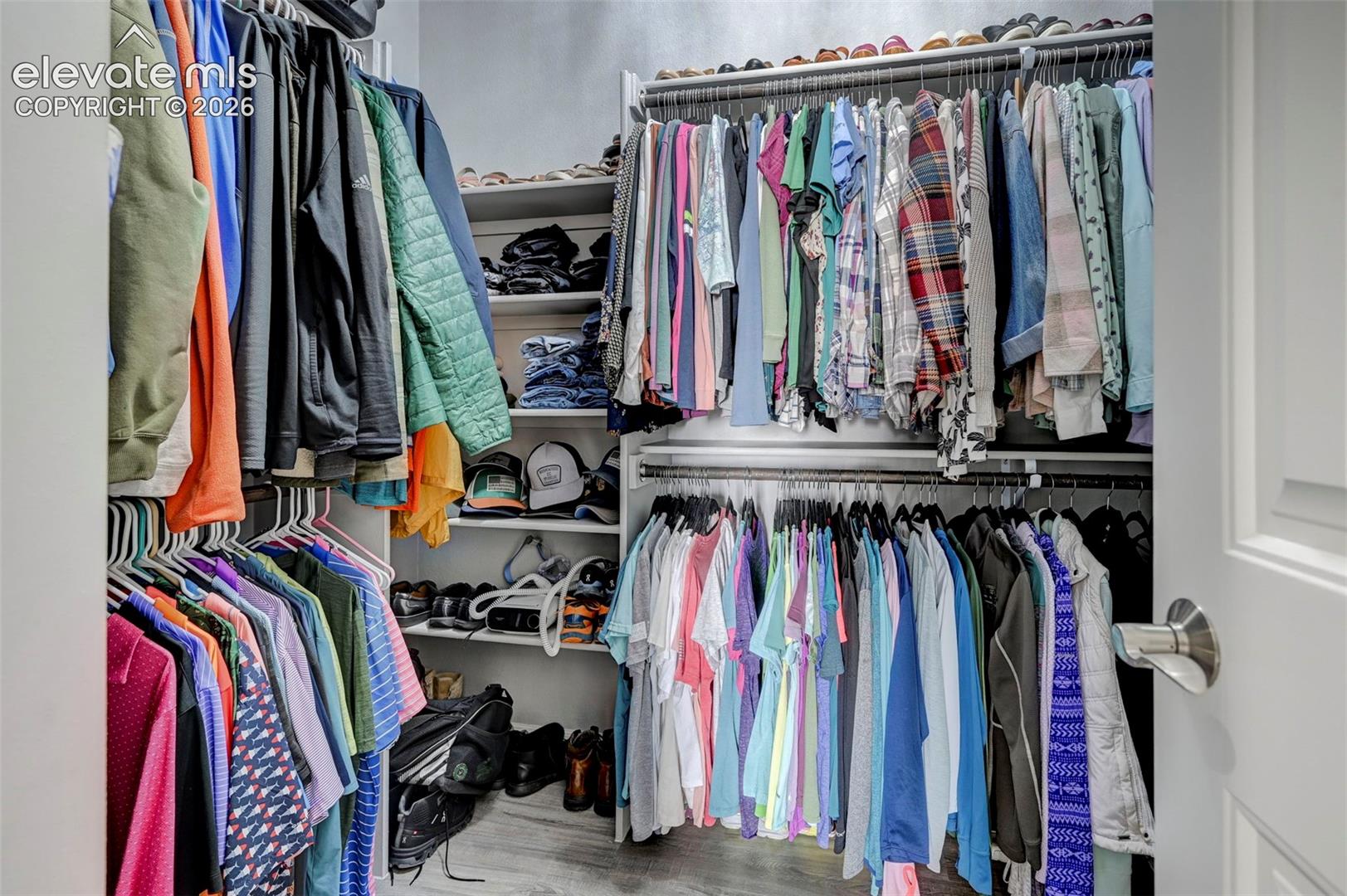 Walk-in closet featuring multiple clothing rods, integrated shelving, and wood-finish flooring