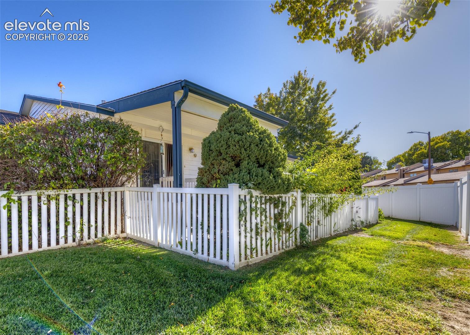 Exterior featuring a covered porch, white picket fencing, and a manicured lawn