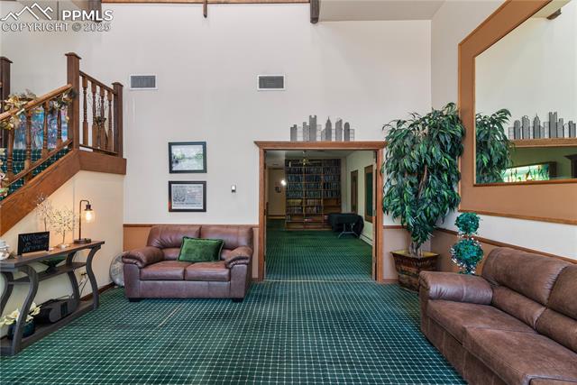 Living area with carpet floors, stairway, and a towering ceiling