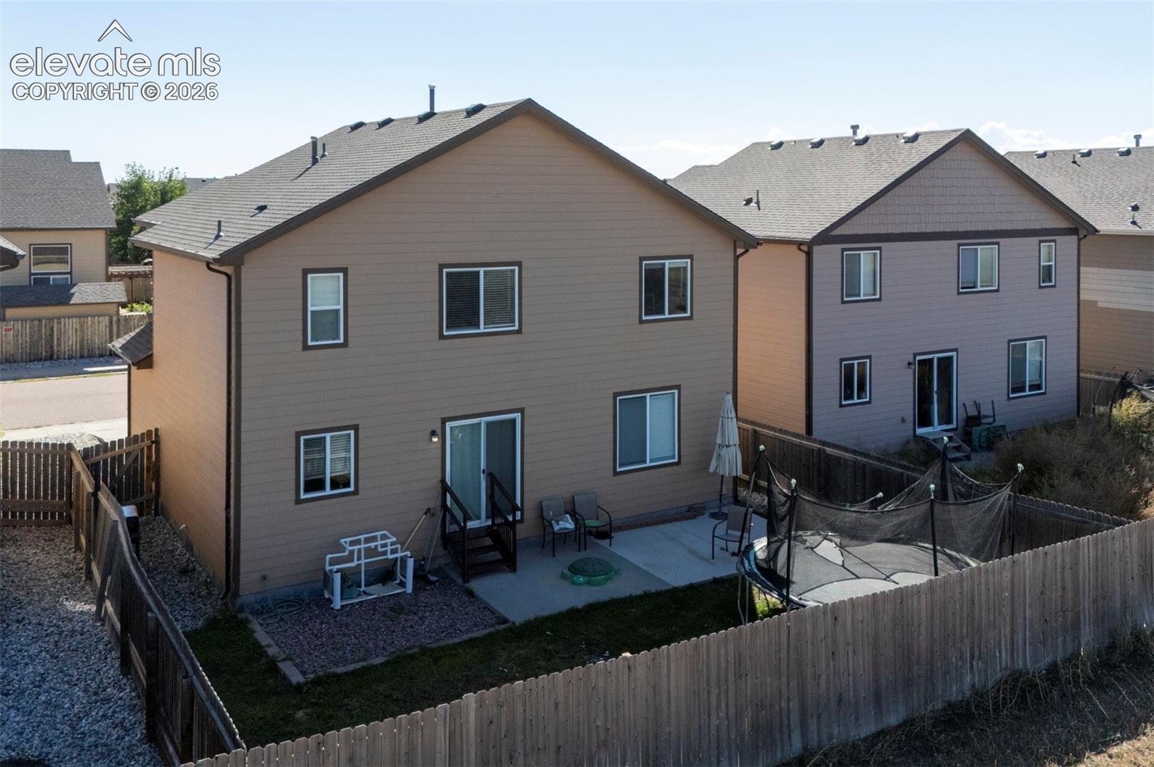 Fenced backyard featuring a concrete patio and a sloped, xeriscaped side yard