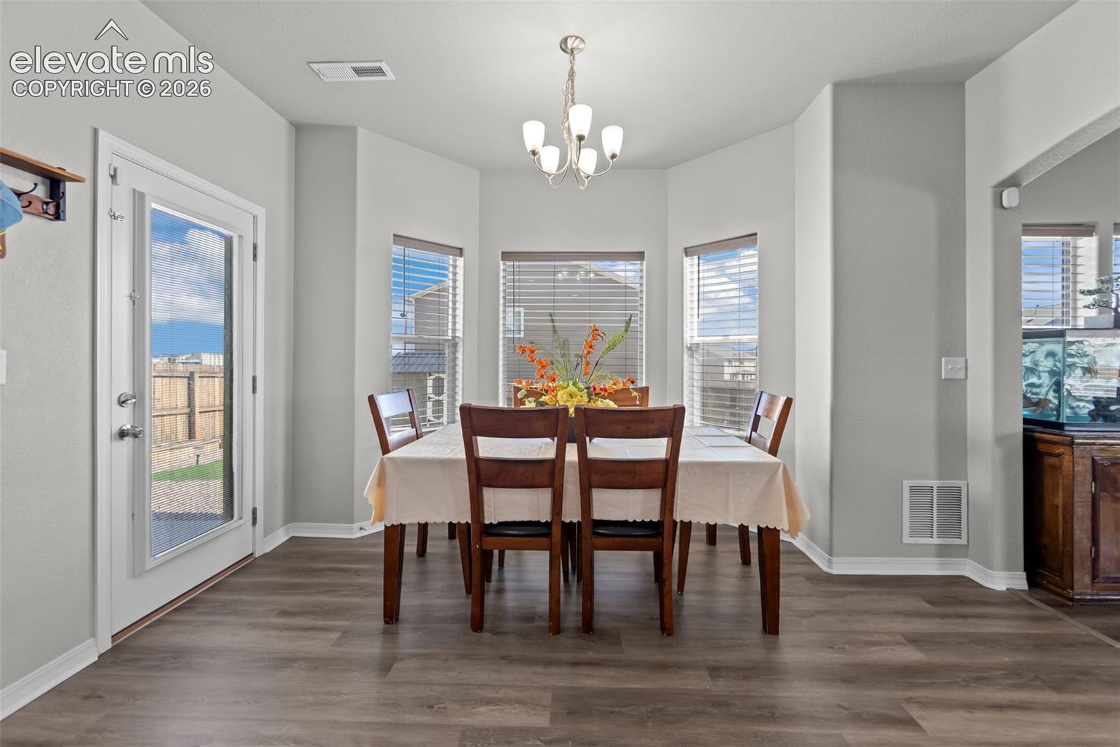 Dining area with wood-finish flooring and a contemporary chandelier