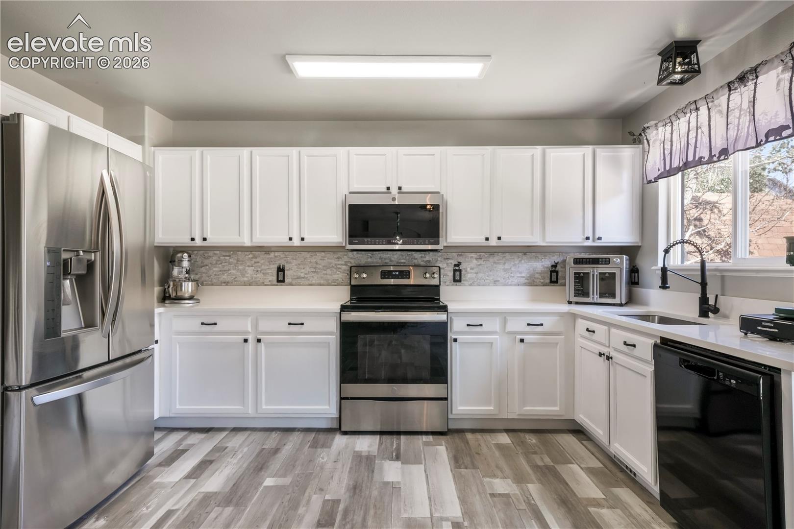 Kitchen with new LVP floors, stainless steel appliances and abundant cabinets and access out to patio