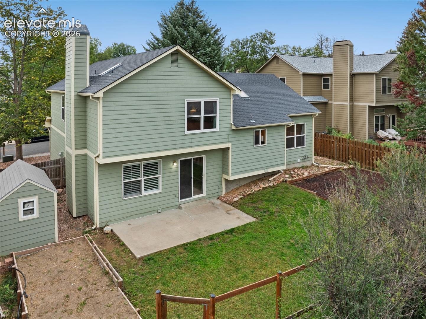 Siding exterior with multiple windows, a concrete patio, and a storage shed