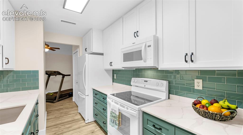 Contemporary kitchen featuring white upper cabinetry, teal lower cabinetry, and a subway tile backsplash