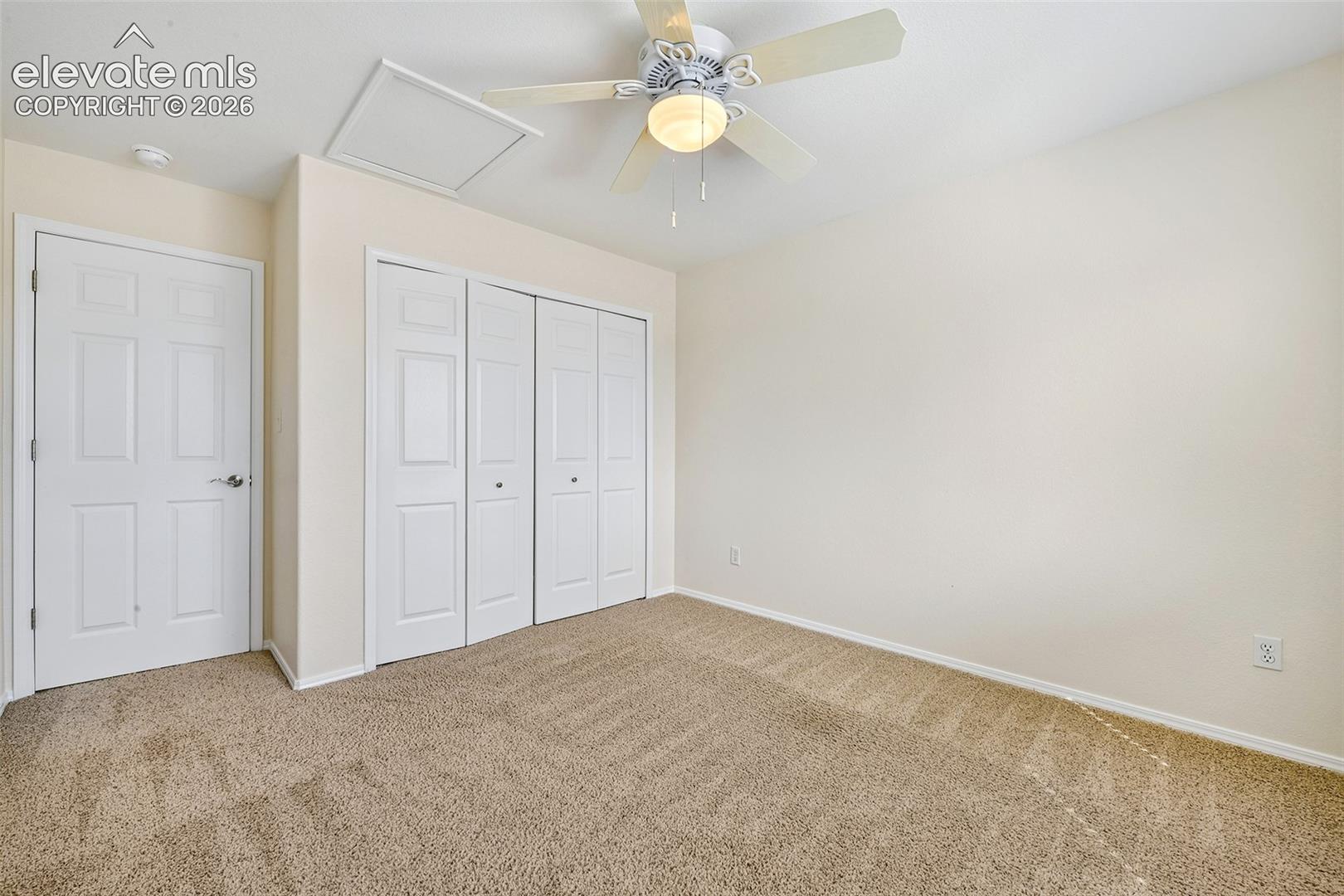 Neutral wall tones, ceiling fan with integrated lighting, textured carpeting, and white bi-fold closet doors