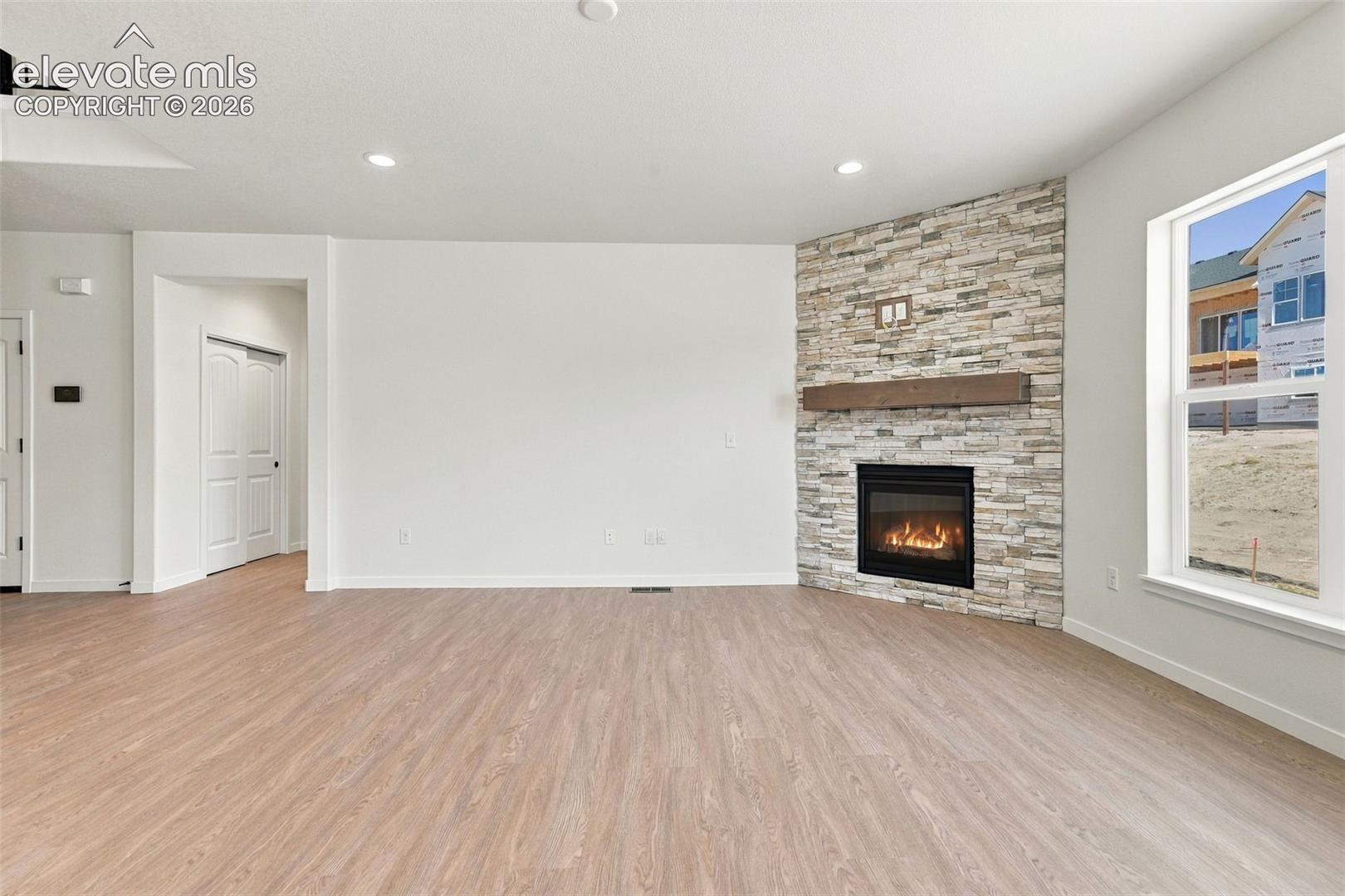 The Great Room features a Gas fireplace with stone extended to the ceiling, wood mantle, LVP Flooring, and recessed lighting.
