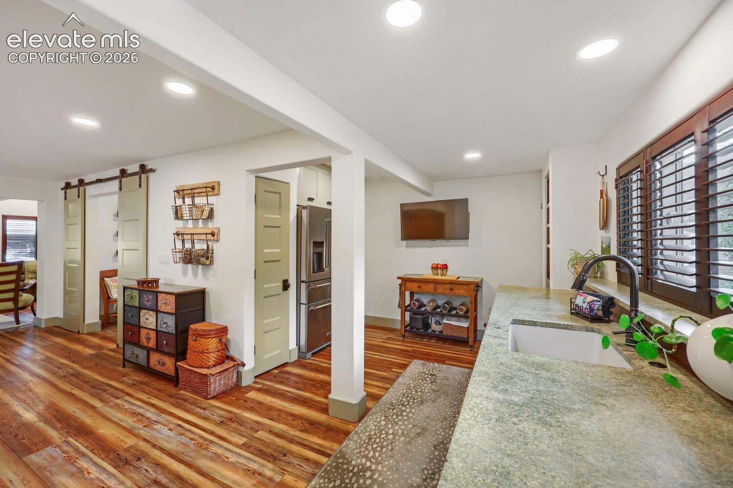 Wood-finish flooring, recessed lighting, and a stainless steel refrigerator
