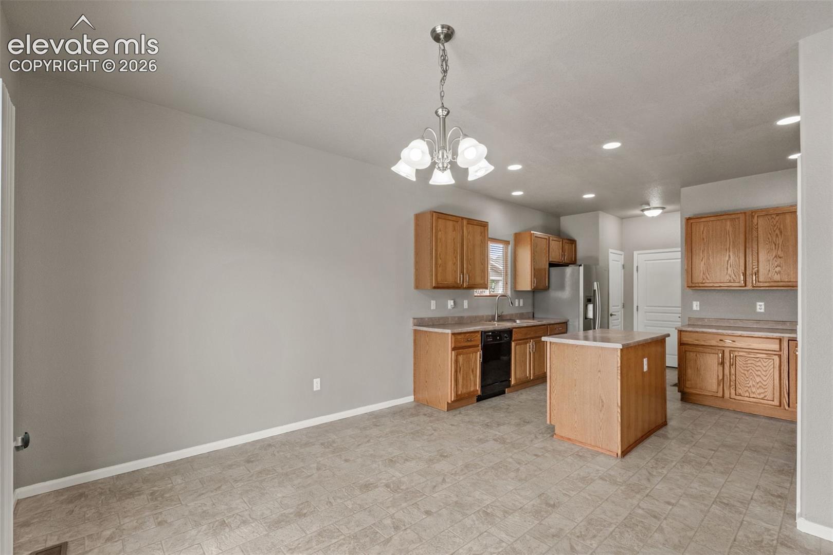Kitchen featuring wood cabinetry, central island, recessed lighting, tile flooring, and a five-light chandelier