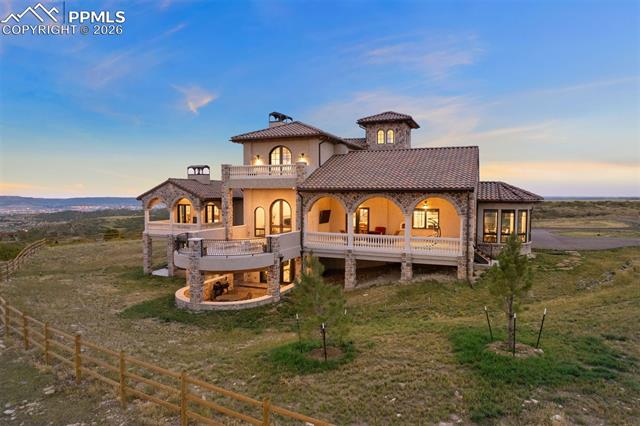 Rear elevation at dusk showcasing the home's multi-level terraces, arched loggia, and crow's nest tower.