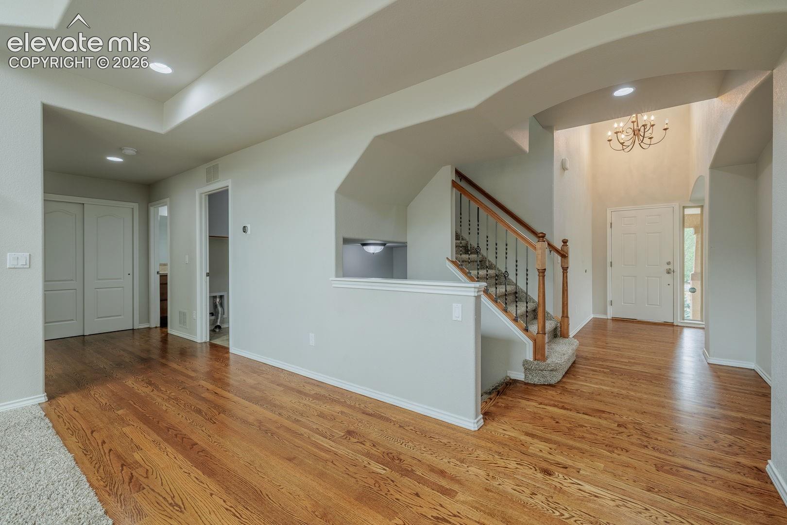 Entryway featuring wood-finish flooring, a two-story ceiling, and an ornate chandelier