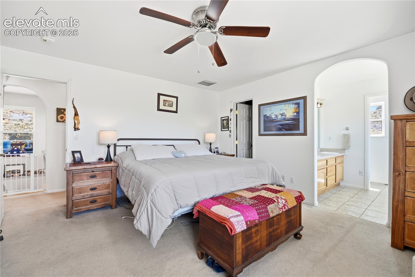 Carpeted flooring, ceiling fan, arched doorway, and white walls