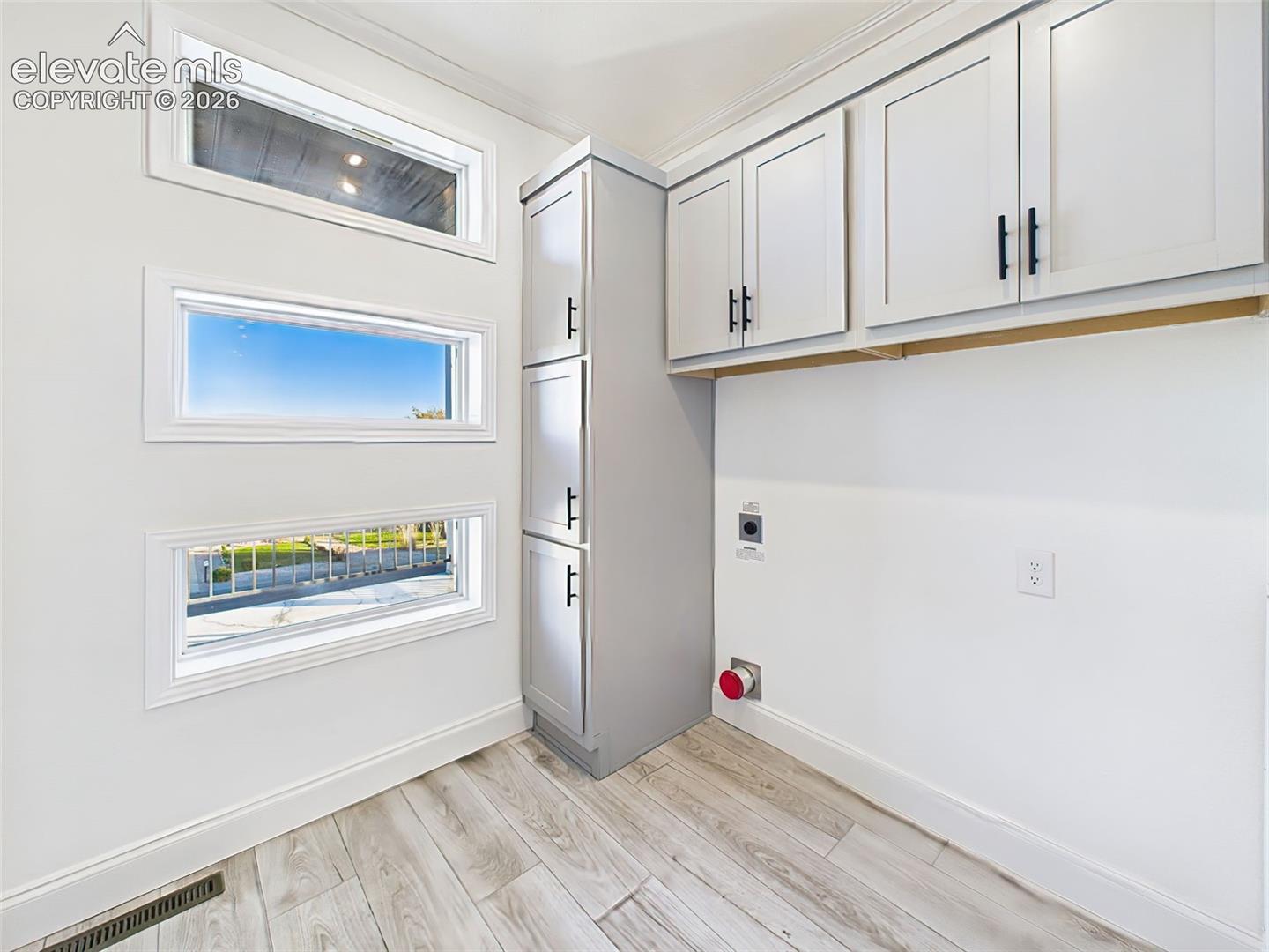 Dedicated laundry space with custom cabinetry, and unique window detail adding natural light.