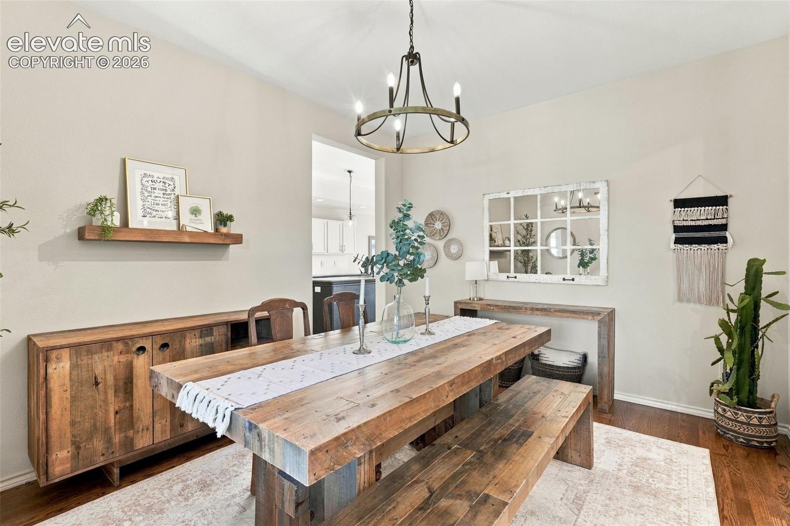 Dining area featuring wood-finish flooring, a six-light iron chandelier, and a built-in wall-mounted floating shelf