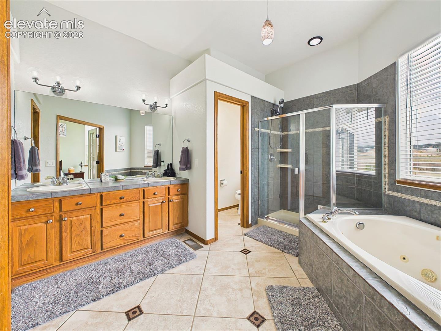 Spa-inspired primary bath featuring dual vanities, a soaking tub, separate tiled shower, and abundant natural light.