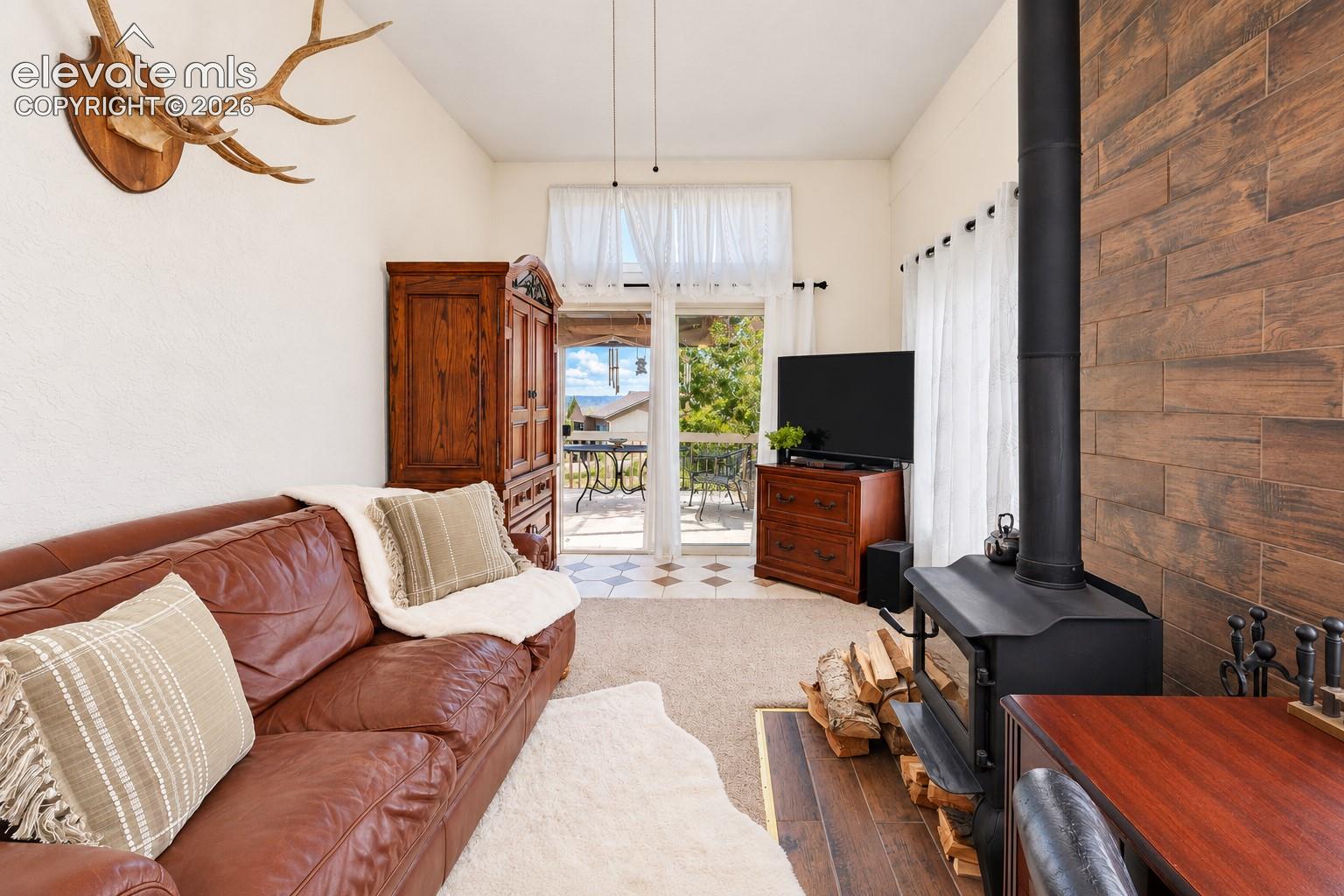 Freestanding black metal wood-burning stove with a horizontal wood-plank accent wall and glass sliding door access to an exterior deck