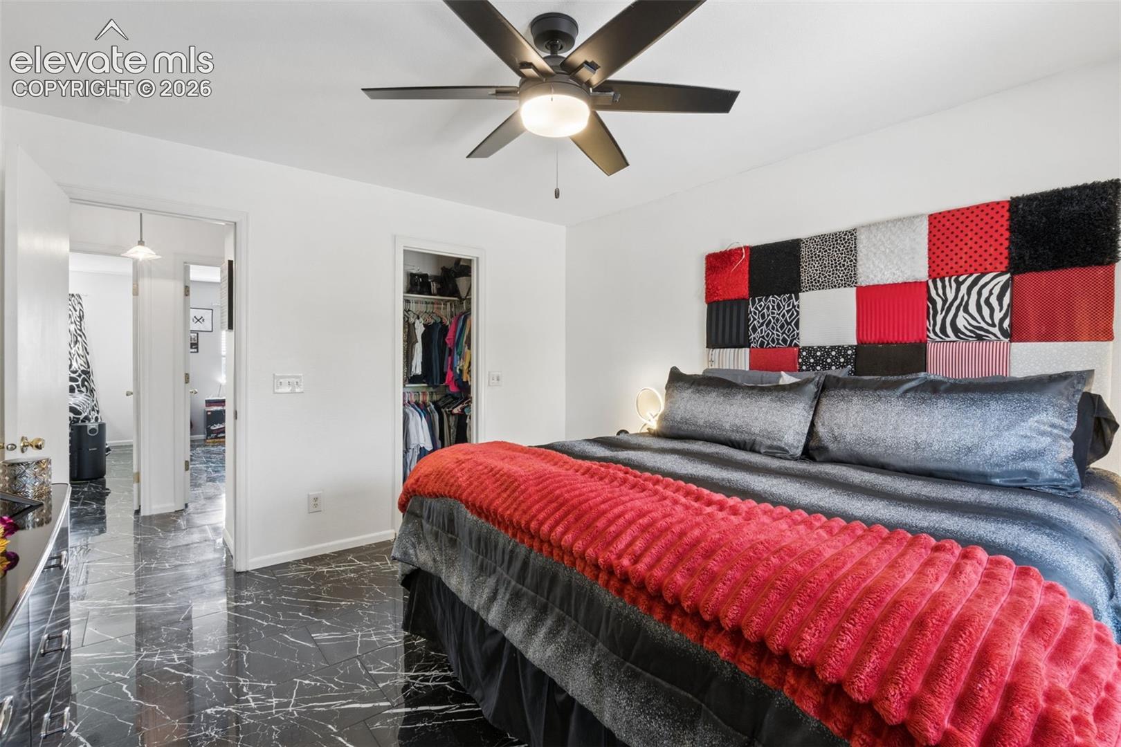 Black marble-effect flooring, ceiling fan with integrated lighting, and white walls